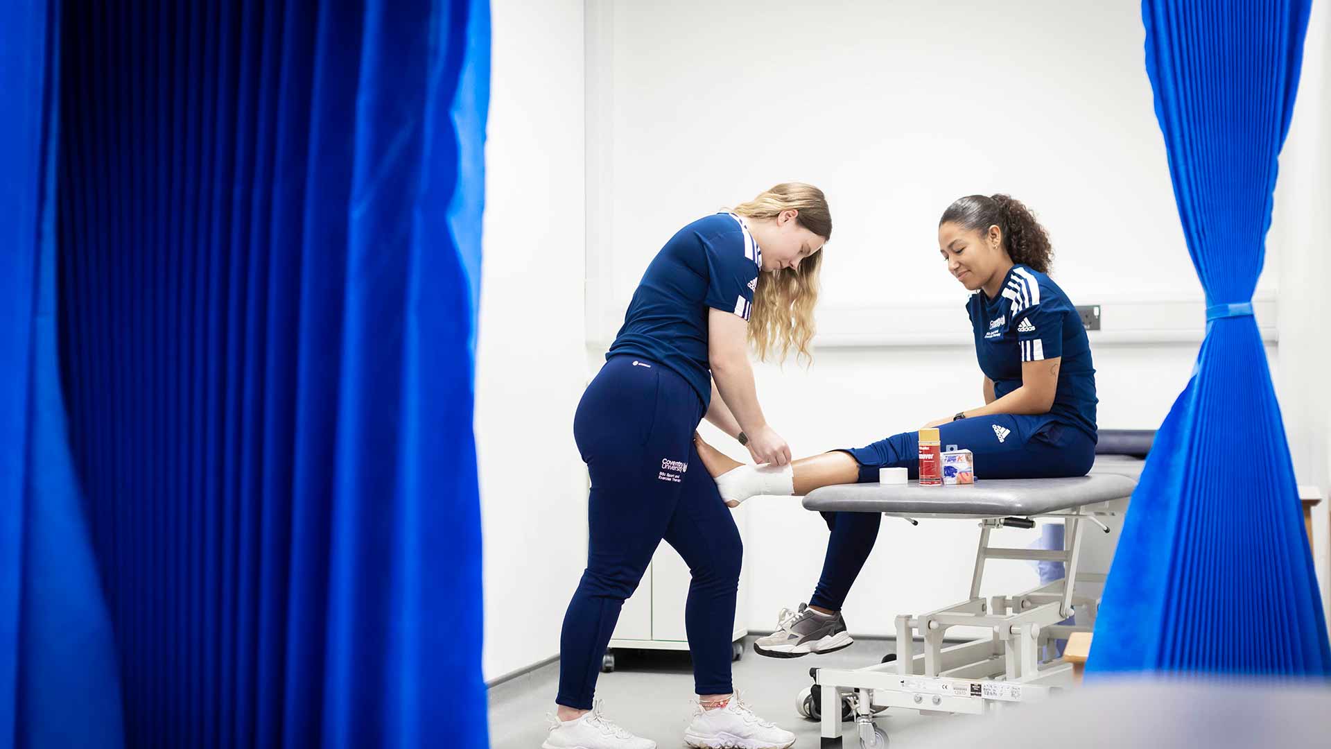 Student putting plasters on another students thigh