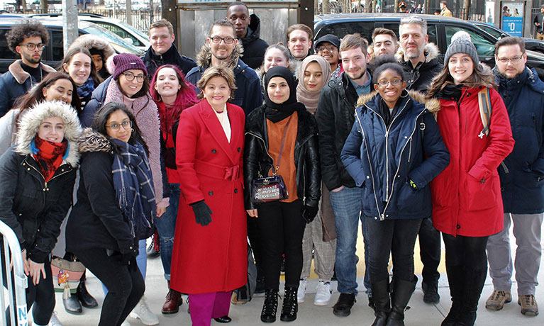 male and female students standing outside  smiling in New York with Gloria Allred