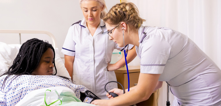 Nursing student taking an actor's blood pressure.