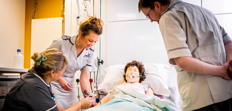 Students and a tutor with a manikin in the hospital ward.
