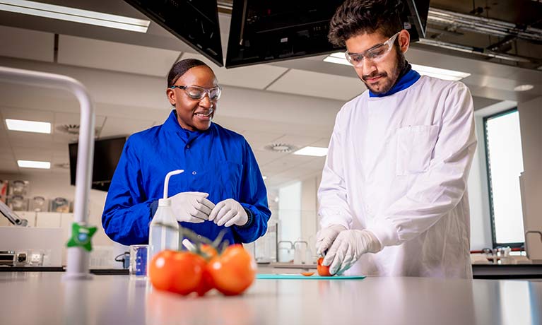 female and male in lab suits in a food science lab 