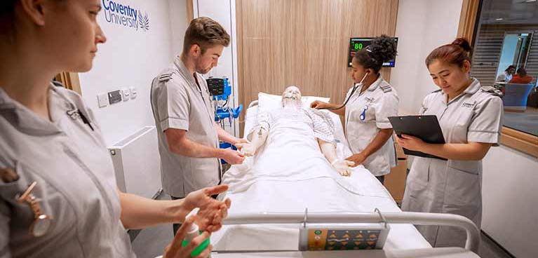 Nurses in training standing around a dummy patient on a hospital bed