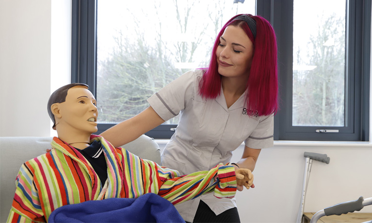 A nursing student working with a manikin in a care environment