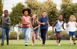 Children laughing as they run across a playing field.