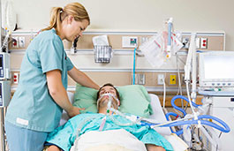 Patient connected to life supporting machine being looked after by a nurse