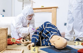 Students in forensic suits working on a simulated crime scene