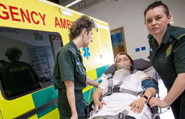 Two paramedic students with a patient on a trolley outside an ambulance