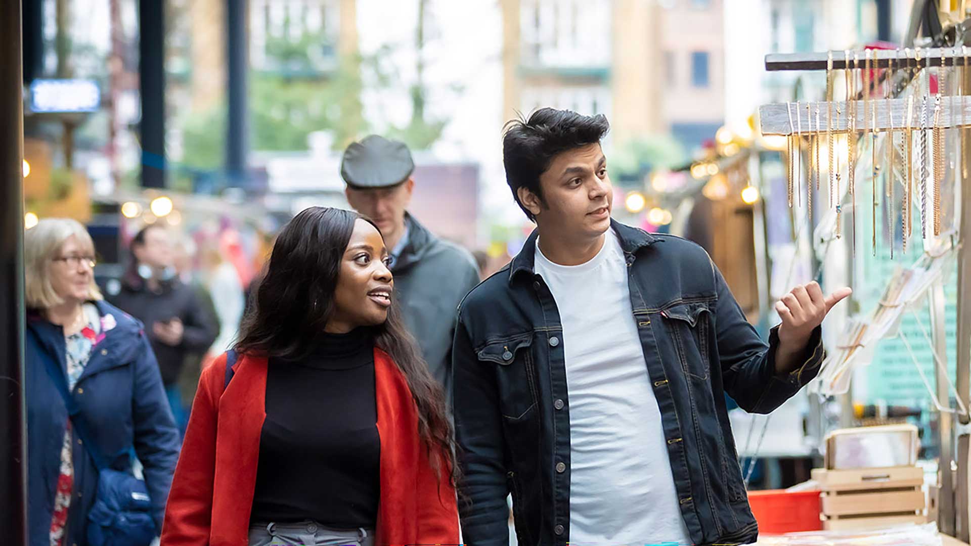 Couple walking on London streets, through a market.