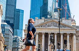 A woman walking in front of the London Exchange.