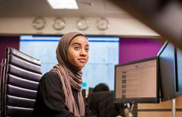 Student wearing a headscarf working at dual screen desktop