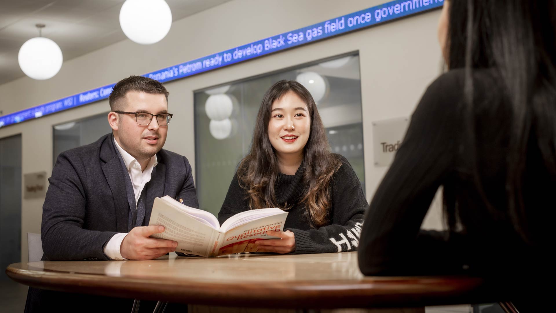 Two students with a textbook on the Trading Floor