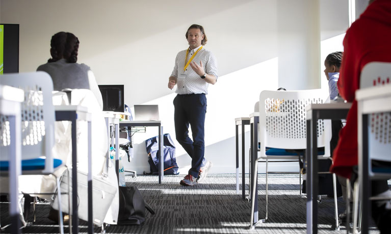 A tutor teaching a class in a bright classroom