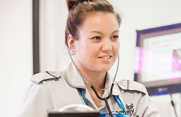 student with a stethoscope and clipboard in the mock hospital ward