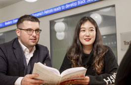 Two students with a textbook on the Trading Floor