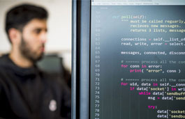 Code on computer screen with student in background