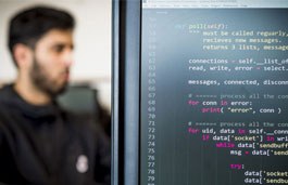 Code on computer screen with student in background