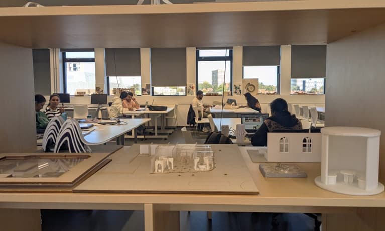 Interior design studio with people working at desks and architectural models displayed in the background