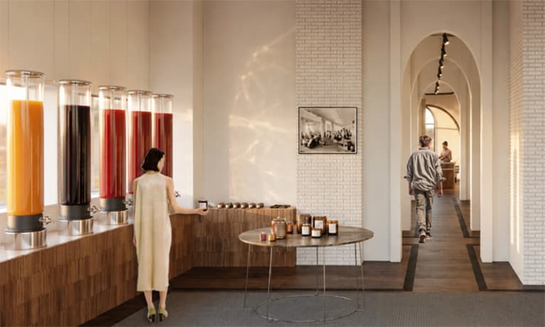 Modern refreshment area with drink dispensers, a wooden counter and an arched hallway with people.
