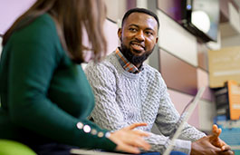 clear view of male student talking to female with laptop turned away from camera