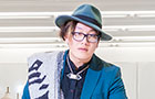 Fashion student wearing a blue hat colourful jacket.