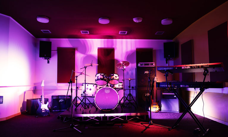drumkit lit under purple lights in a music room