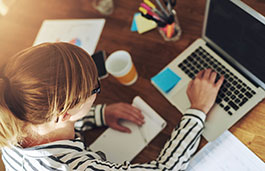 A woman working at her laptop with a cup of coffee