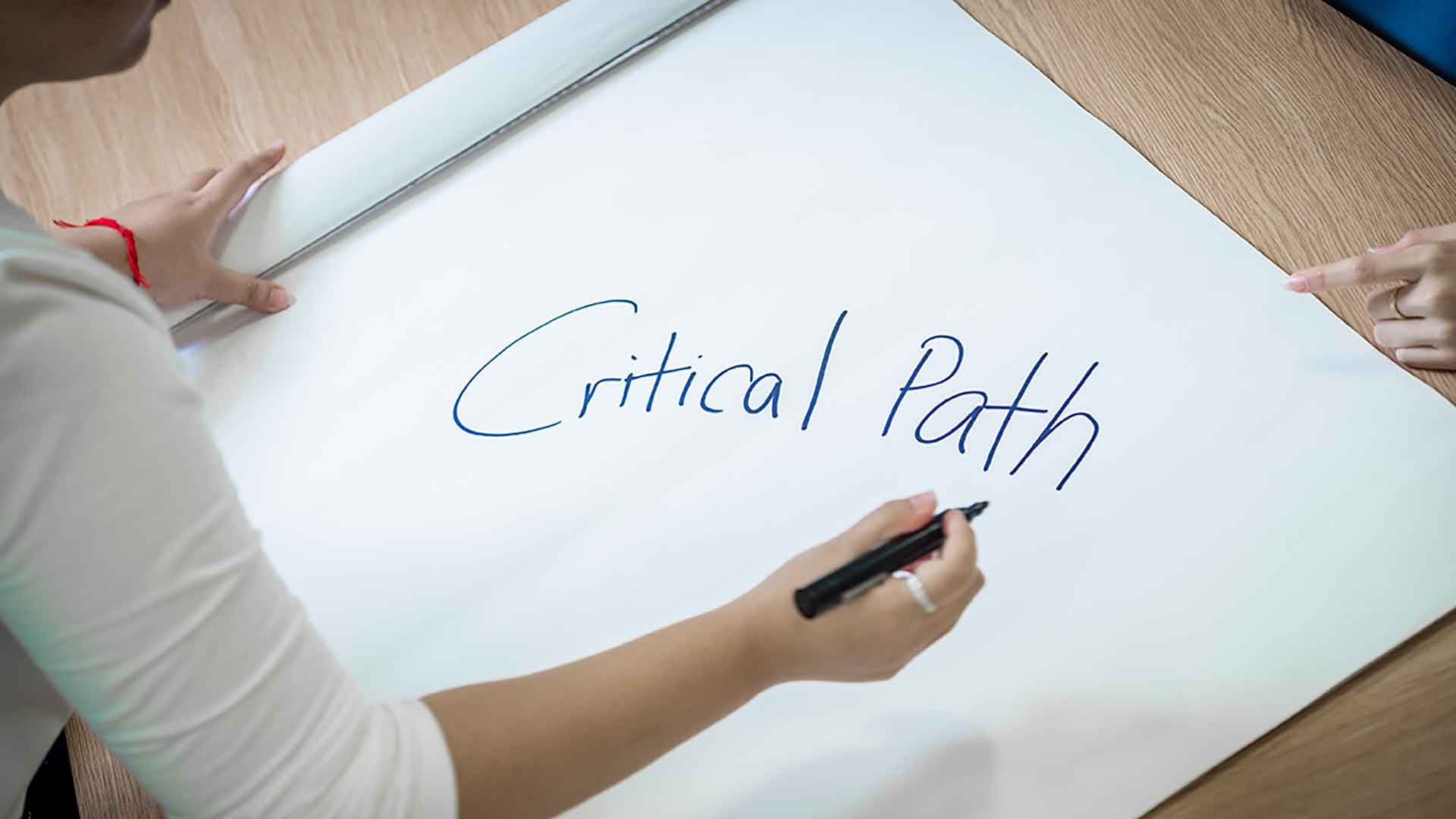 student writing critical path on white board 