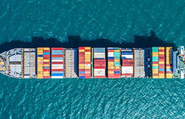 Container ship loaded up with colourful containers, water either side