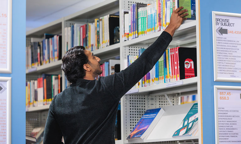A man reaching for a book in a library