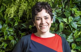 Woman standing smiling against a hedge