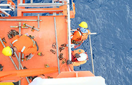 Three workers in construction gear on platform above water