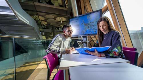 Male and female looking at aviation management charts in a building with a lot of windows