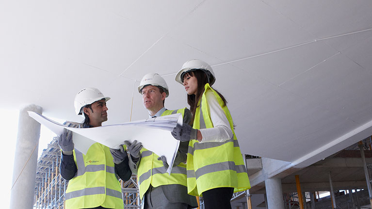 three people in high vis vests reading a report