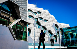 A silhouetted person walking past a modern architecture building wearing a suit