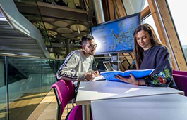 Male and female looking at aviation management charts in a building with a lot of windows