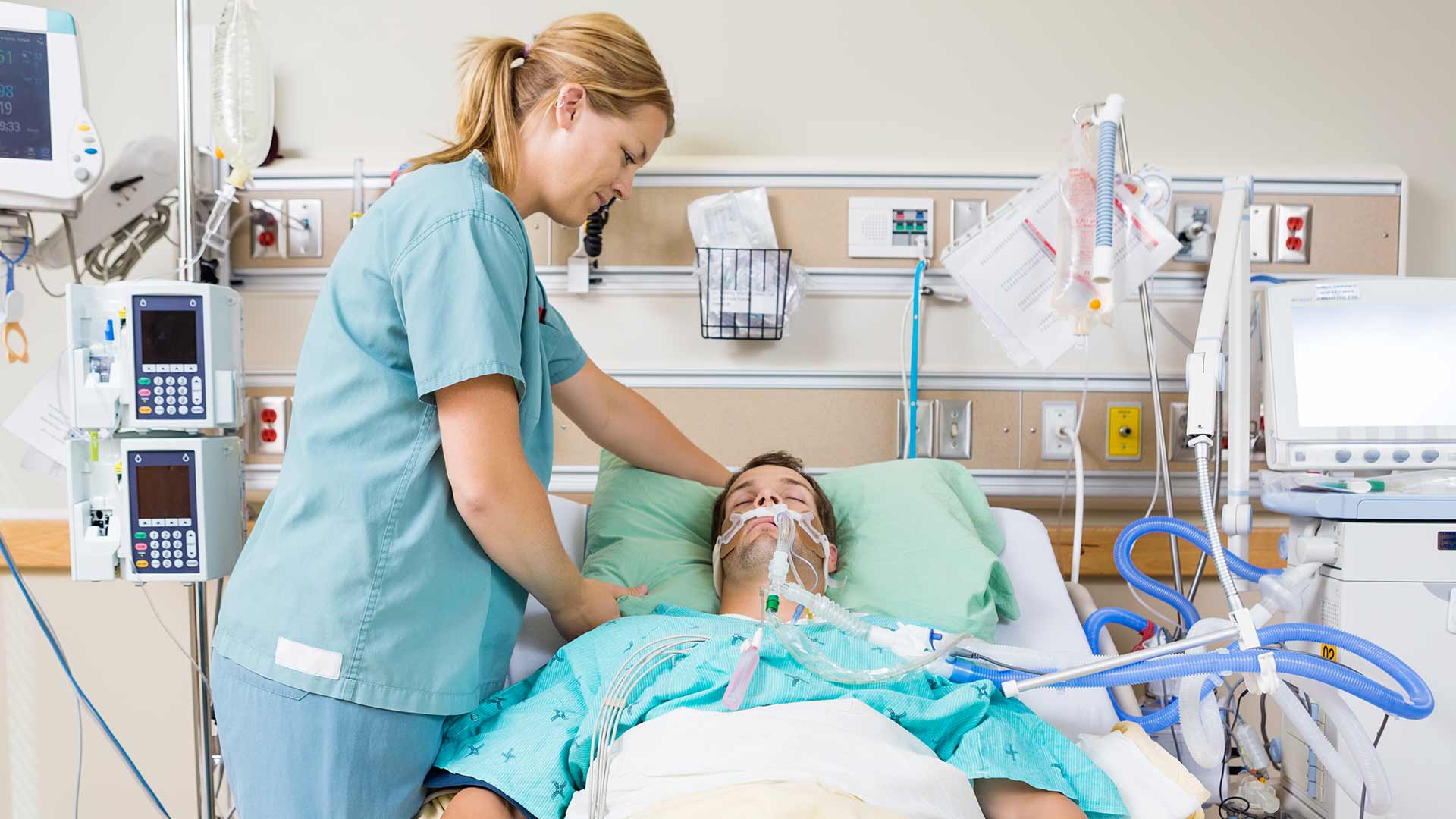 Patient connected to life supporting machine being looked after by a nurse