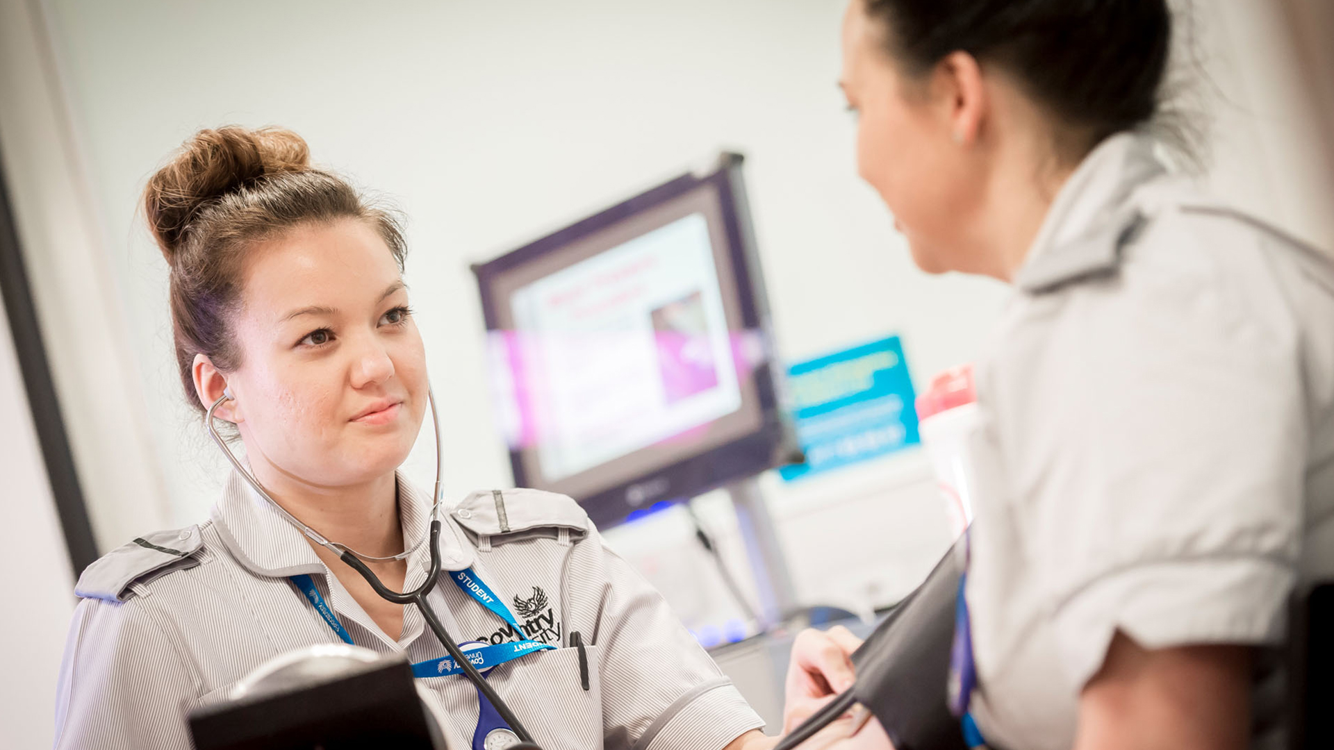 Nurse behind a desk smiling at another staff member