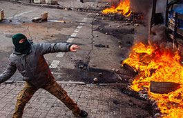 Man protesting in front of a burning wall