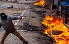 Man protesting in front of a burning wall