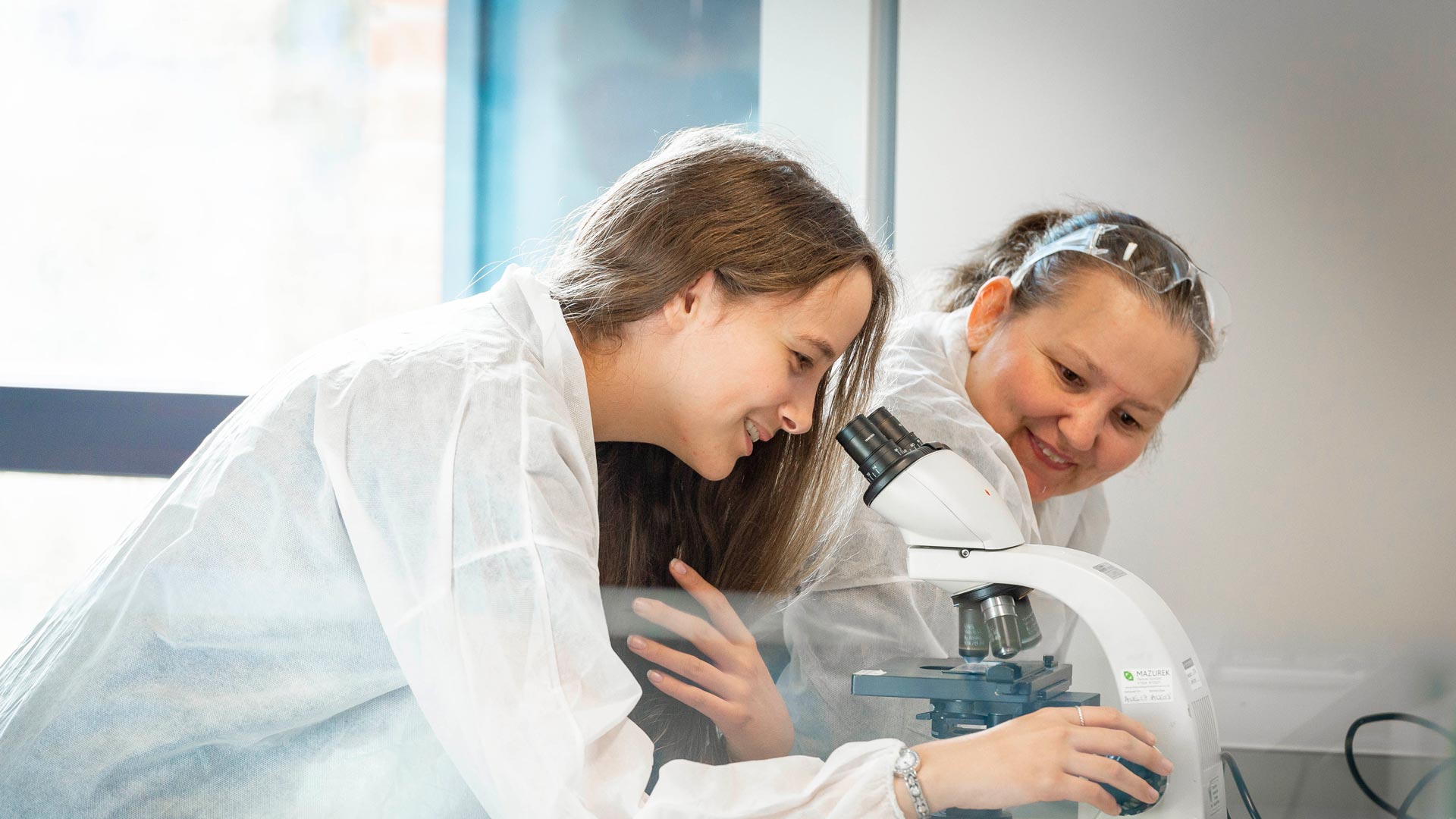Two female pharmacologists one working with a microscope