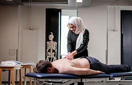 Female giving a back massage to a person lying on a massage bed