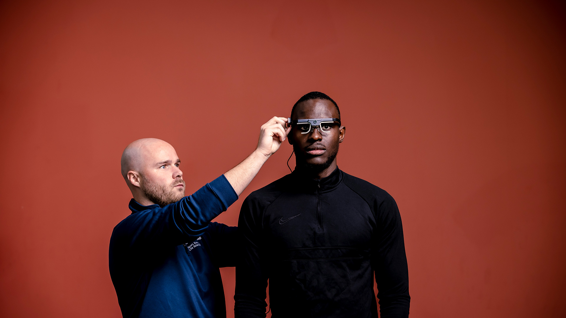 Male adjusting a pair of glasses on another persons head