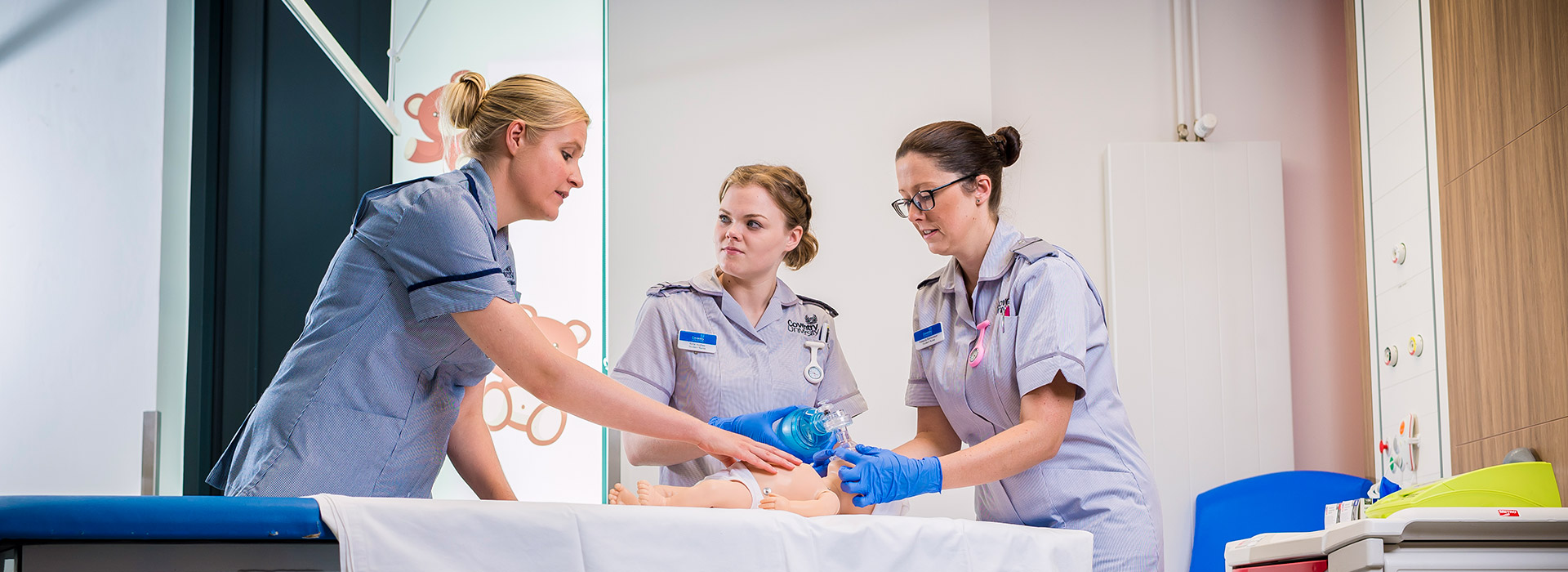 Three nurses in training on a fake baby 