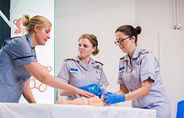 Three nurses in training on a fake baby 