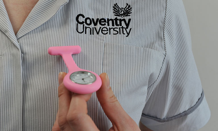 Close up of person in Coventry University uniform lifting a watch fob