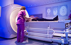female in scrubs preparing a patient who is lying down in a CT scanning machine