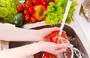 A pair of hands washing fruit and vegetables