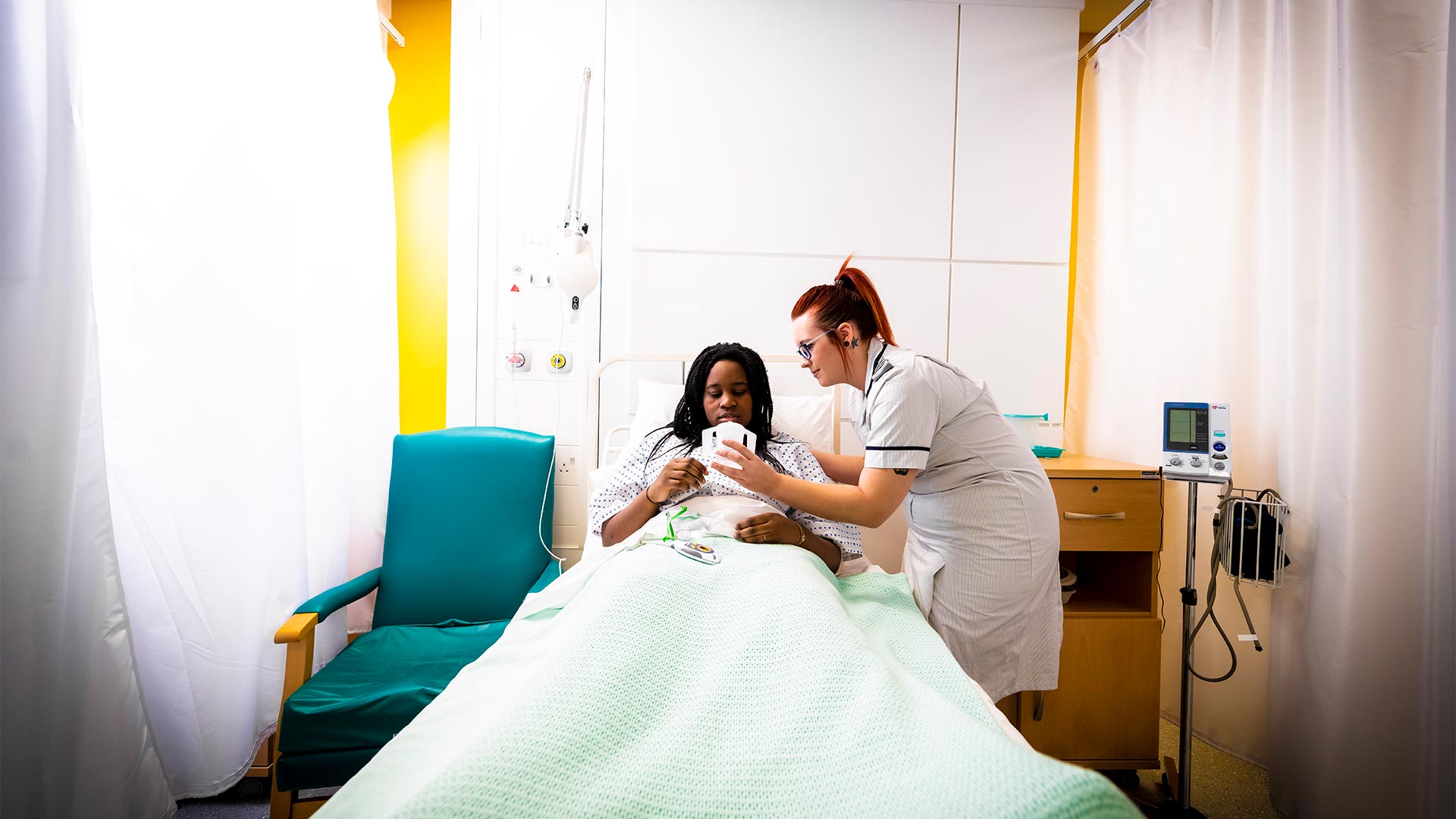 Nursing staff providing updates to a patient who is lying on a bed