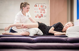 A physiotherapist working on a patient lying down receiving treatment