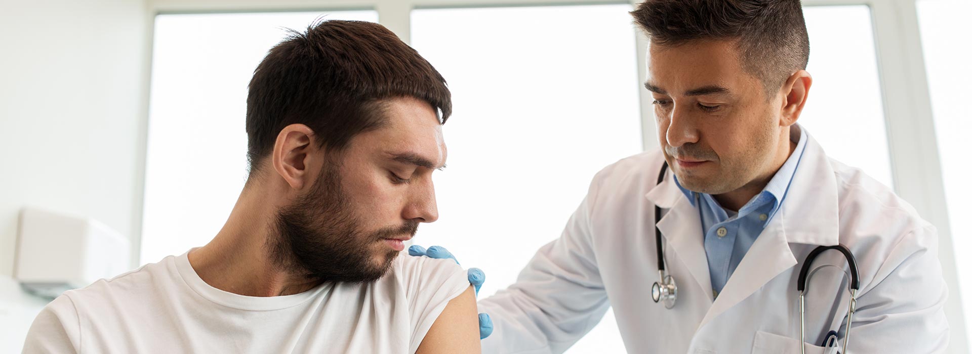 Doctor administering a vaccine to a male patient